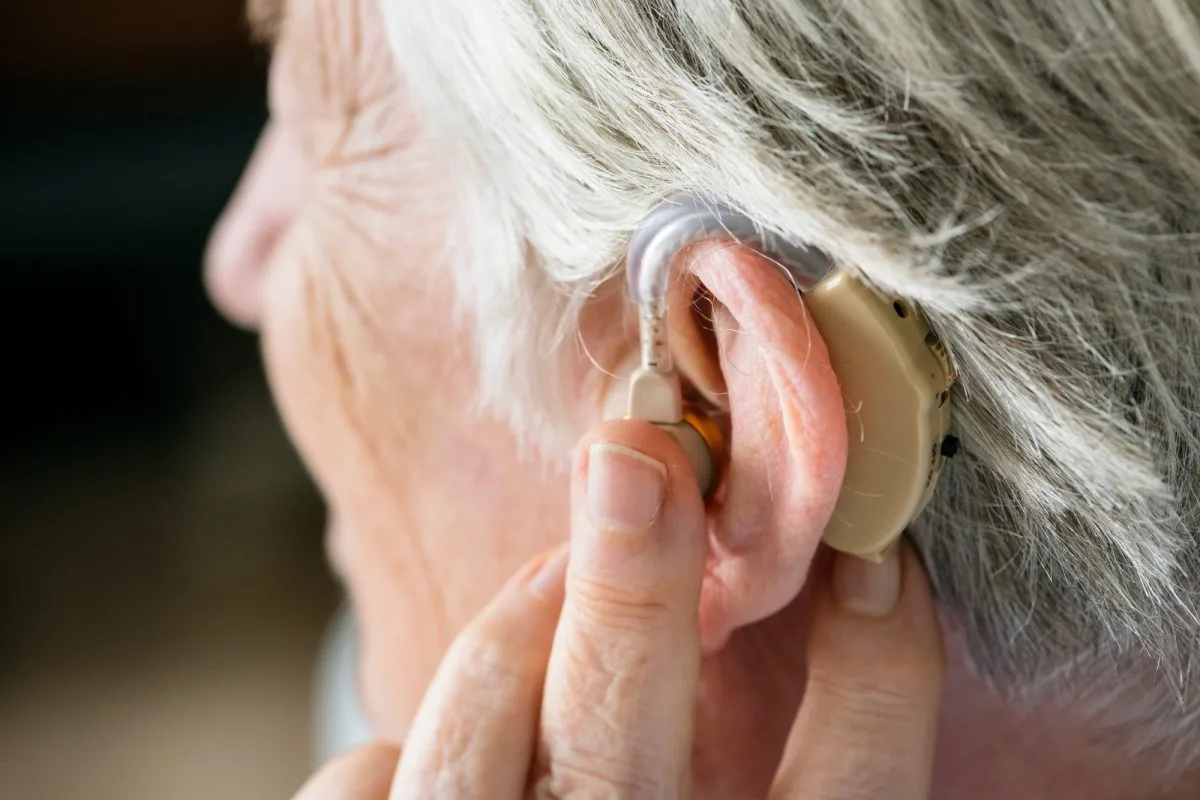 Femme âgée portant un appareil auditif avec un sourire satisfait